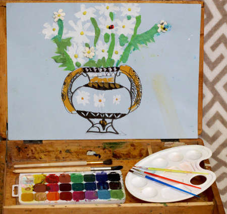easel with paints, painting with a vase and white flowers on a blue backgroundの写真素材