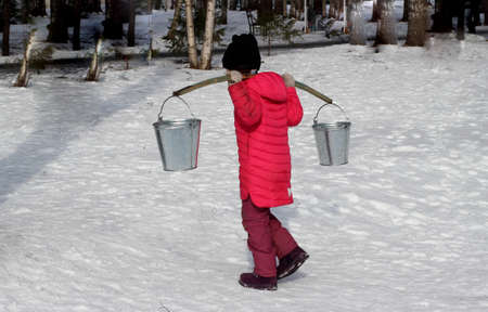 girl carries a rocker with two buckets on her shouldersの写真素材