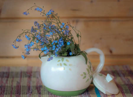 Blue flowers in a white teapot on a woven rug, selective focusの写真素材