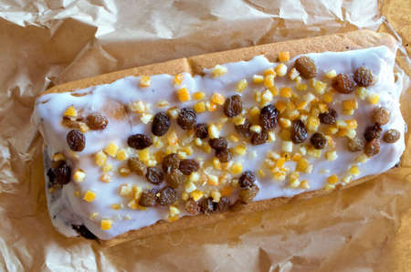 the poppy seed cake with icing and dried fruits lies on the paper