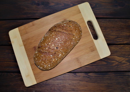 A loaf of bread on a cutting board on a wooden background.
