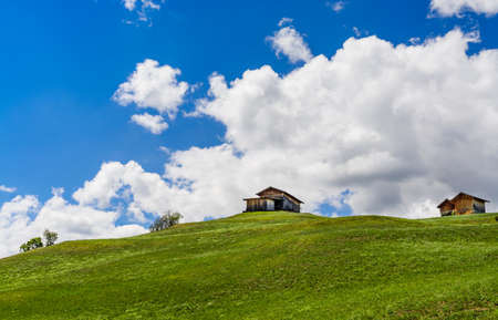 Alpine landscape with traditional cabins, blue sky and clouds on the backgroundの写真素材