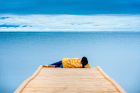 Girl sitting on the wooden pier and looking at lake Baikal.