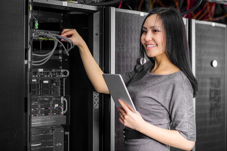 Young engineer businesswoman with tablet in network server room