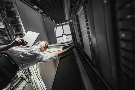 Young engineer businesswoman in network server room. Russia.