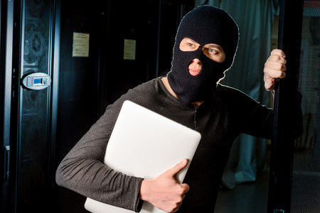 Hacker in a mask inside a datacenterの写真素材