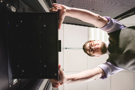 Young engineer wearing glasses in a datacenter