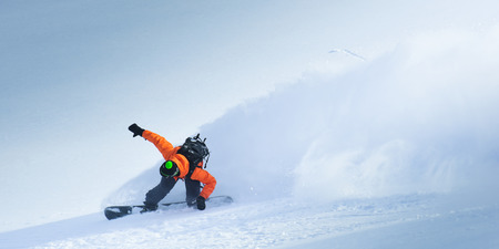 Snowboarder going down the hill on the winter