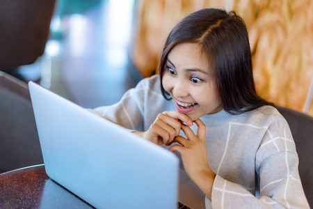 Young beautiful happy asian woman using laptopの写真素材
