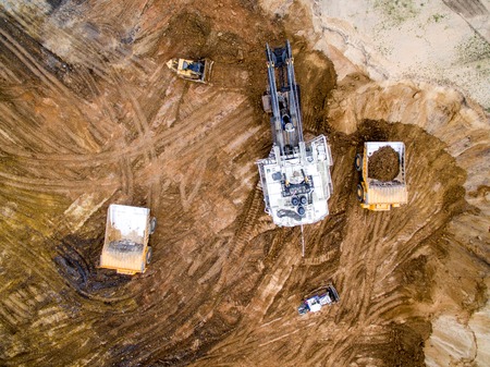 An excavator loading big truck with ground in open pitの写真素材
