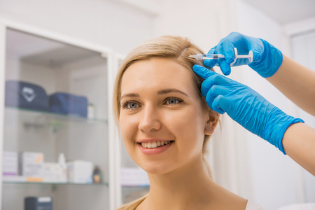 Young female patient getting head injections in a hospitalの写真素材