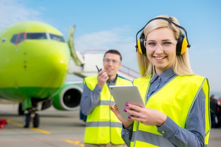 Aircraft workers with radio standing in front of a commercial airliner