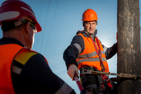 RUSSIA - OCTOBER, 2016: Electrician lineman repairman worker at climbing work on electric post power poleのeditorial素材