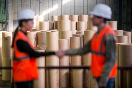 Paper mill factory workers with giant paper rolls on the backgroundの写真素材