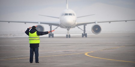 airport worker directing an airplane as it arrivedの写真素材