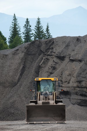 Excavator at an open pit with pile on the background