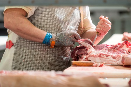 Worker cuts meat butcher handling cuts of prime choice cutsの写真素材