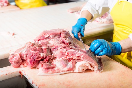 Worker cuts meat butcher handling cuts of prime choice cuts