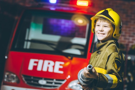 A boy wearing a firefighter uniform smilingの写真素材