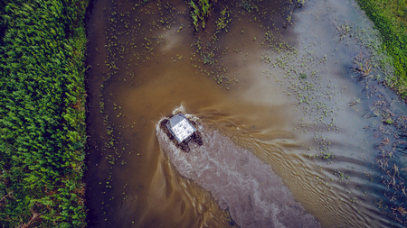 An off-road vehicle sails on the river. aerial above view topの写真素材