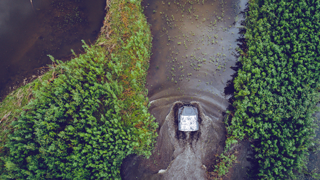An off-road vehicle sails on the river. aerial above view topの写真素材