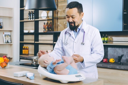 doctor weighting cute baby at homeの写真素材