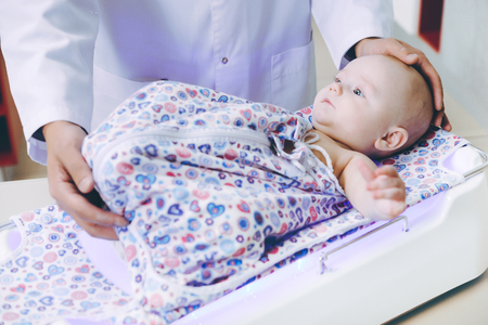 doctor weighting cute baby at homeの写真素材