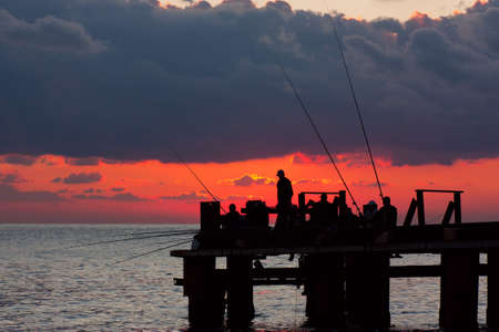 Fishermans on a pier in the evening on a seaの写真素材