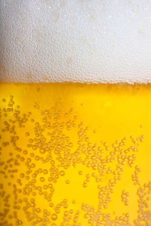 Orange beer and white froth background. Closeup view.