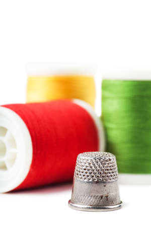 Closeup view of thimble and colorful spools over white backgroundの写真素材