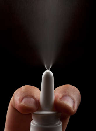 Bottle of nasal spray while spraying over black backgroundの写真素材