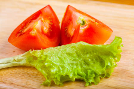 Cutted tomato and salad leaf on a wooden tableの写真素材