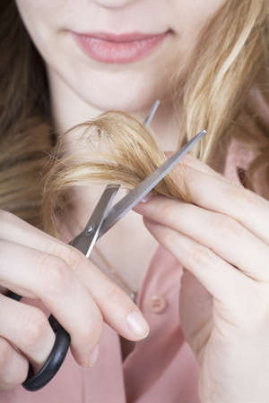 Young woman cutting her hair with scissorsの写真素材