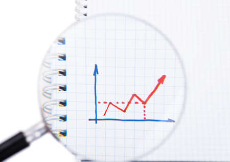 Graph drawn by hand on paper shit under magnifying glassの写真素材