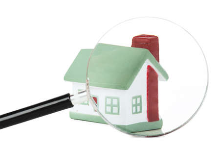 Toy of house and hand with magnifying glass isolated over white backgroundの写真素材