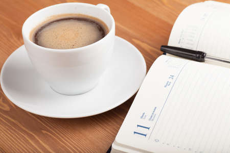 Notebook with pen and cup of coffee on a table  Top viewの写真素材