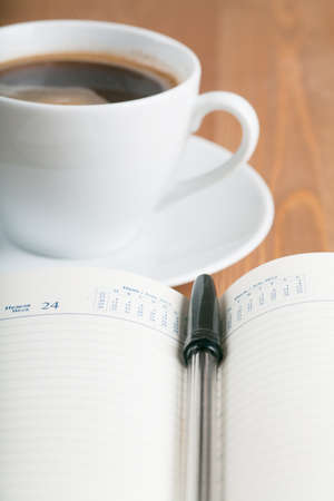 Notebook with pen and cup of coffee on a table. Top viewの写真素材