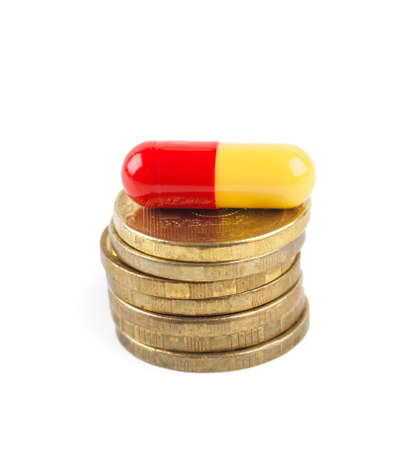 Closeup view of stack of coins and pill over white backgroundの写真素材