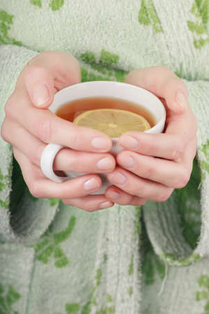 Cup of tea with lemon in woman handsの写真素材