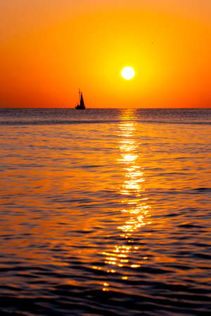 Single yacht in the sea at sunsetの写真素材
