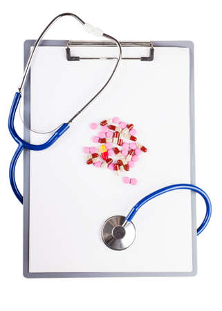 Blank sheet on clipboard with pills and stethoscope over white backgroundの写真素材