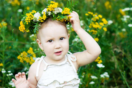Portrait of a little girl in a wreath from wild flowers. Child closeup.の写真素材