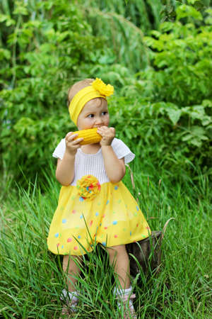 The child eats the corn in nature. Funny little girl eats in the Park.の写真素材
