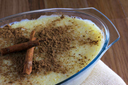 Closeup of rice pudding with cinnamon on wooden table, leaning on fabric
