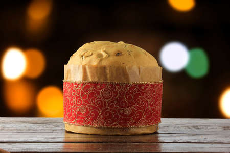 panettone, decorative food, on wooden table, blurred lights in the background, front viewの写真素材