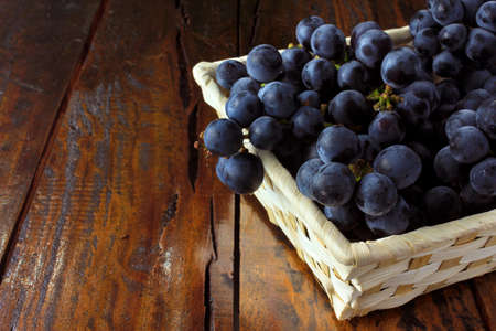 bunches of grapes, inside bamboo fiber basket on wooden table, closeup view