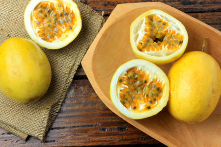 yellow passion fruit and passion fruit cut in half in wooden bowl on wooden table.Top viewの写真素材