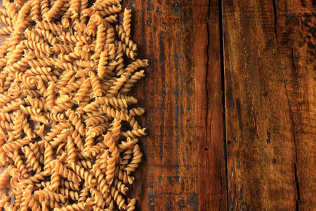 Top view Wholemeal pasta fusilli raw organic whole grain on a rustic wooden. Whole wheat pasta, copy spaceの写真素材