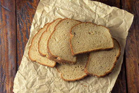 Sliced organic wholemeal bread, made of oats and flax seeds on paper. Healthy diet. Top View