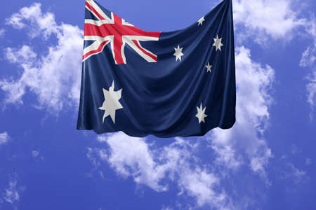 National flag of Australia hoisted outdoors with sky in background. Australia Day Celebration. Front...